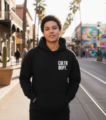 Person wearing a black hoodie with 'CULTR DEPT.' text on a street with palm trees and a mural.
