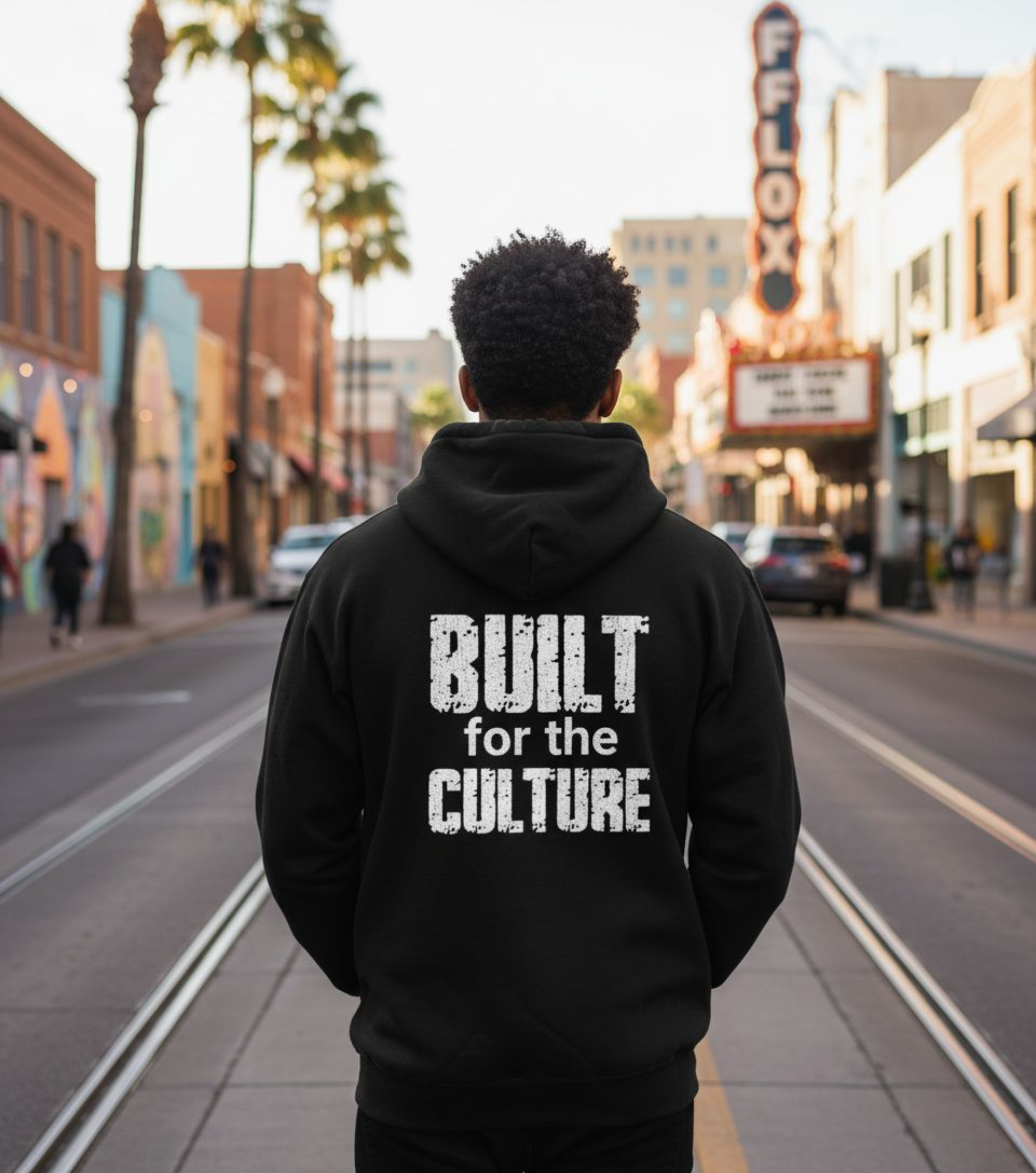 Person wearing a black hoodie with 'Built for the Culture' text on a city street.