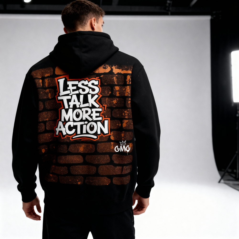 Person wearing a black hoodie with 'Less Talk More Action' text on the back, studio setting