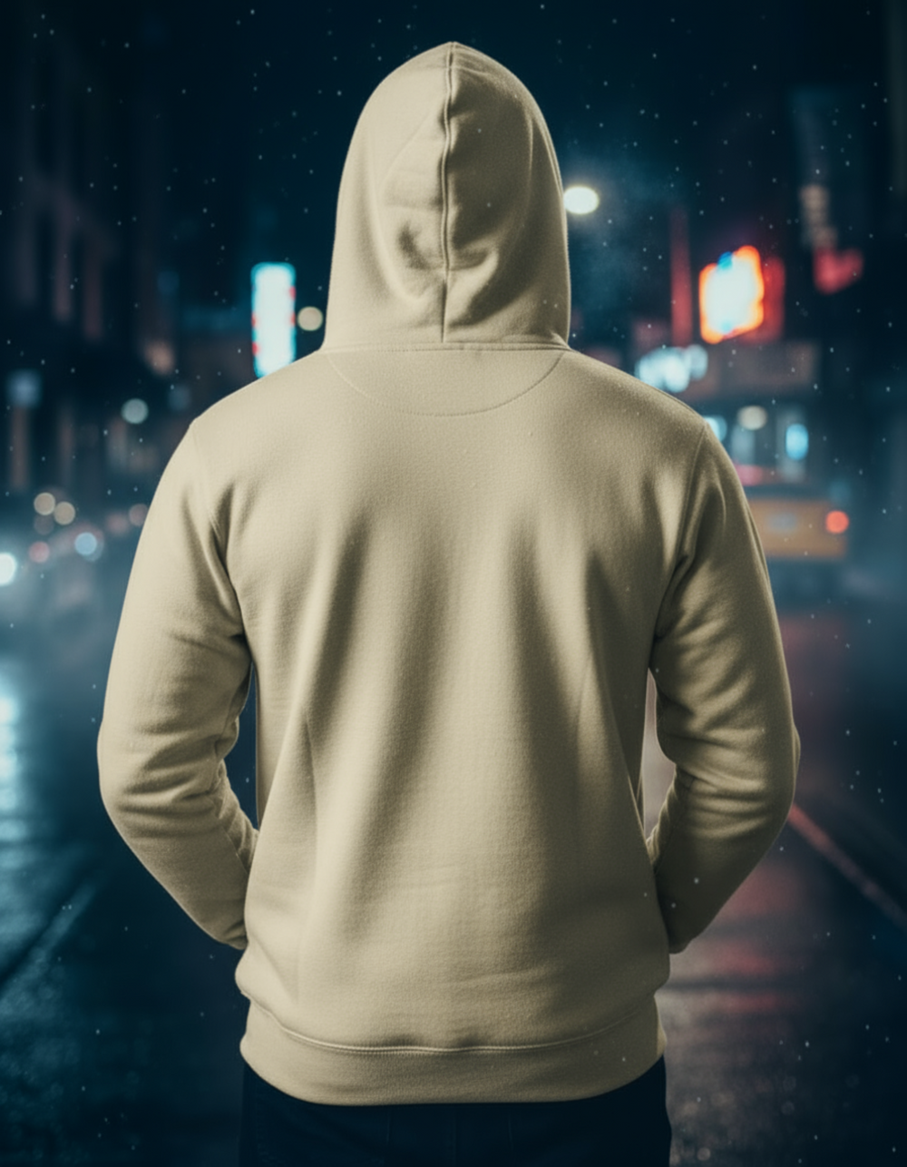 Person wearing a beige hoodie with a cityscape in the background at night.