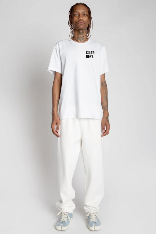 Person wearing a white t-shirt with text and white pants on a plain background