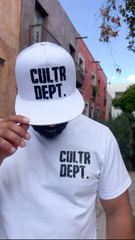 Person wearing a white cap and t-shirt with 'CULTR DEPT.' text in an urban setting.