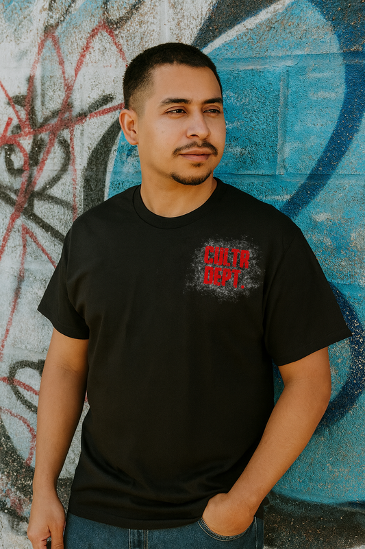 Man wearing a black t-shirt with a logo in front of a graffiti-covered wall